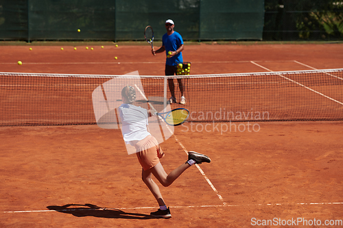 Image of A professional tennis player and her coach training on a sunny day at the tennis court. Training and preparation of a professional tennis player