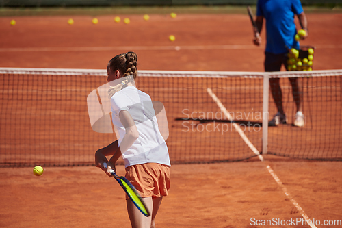 Image of A professional tennis player and her coach training on a sunny day at the tennis court. Training and preparation of a professional tennis player