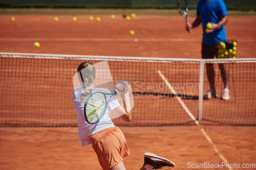 Image of A professional tennis player and her coach training on a sunny day at the tennis court. Training and preparation of a professional tennis player