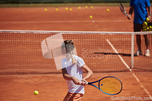 Image of A professional tennis player and her coach training on a sunny day at the tennis court. Training and preparation of a professional tennis player