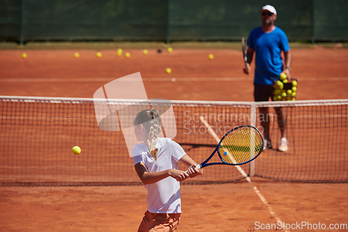 Image of A professional tennis player and her coach training on a sunny day at the tennis court. Training and preparation of a professional tennis player