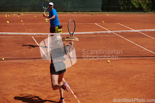 Image of A professional tennis player and her coach training on a sunny day at the tennis court. Training and preparation of a professional tennis player