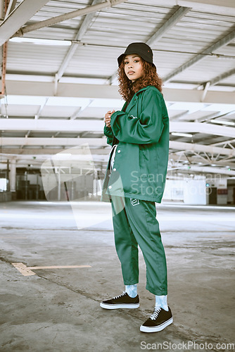 Image of Portrait, fashion or stylish young gen z woman stand in a warehouse with green clothing. Trendy, hipster latino girl with attitude and curly hair in industrial building or factory with pride or cool