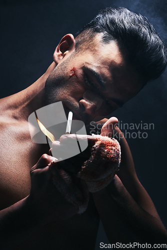 Image of Boxer, man and cigarette smoking after fight, blood and bandage from injury against a black studio background. Fighter smoke after boxing, training or mma match with bruise, violence and blood scar