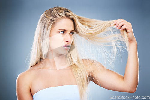 Image of Upset, angry and annoyed woman with hair problem or style issue on a grey studio background. Damage, bad and expression of female unhappy with blonde hair loss for advertisement on a backdrop