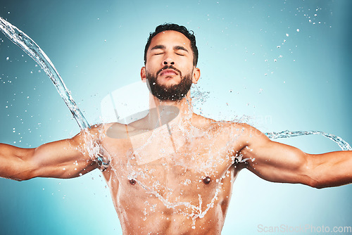 Image of Muscular man, water splash and wellness for fitness and health with blue studio background. Hygiene, male athlete and bodybuilder wash clean, shower and body care after workout, training and exercise