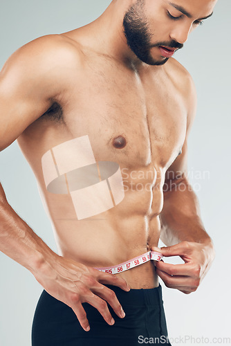 Image of Man, measuring and tape for weight loss, goal and body wellness and healthy lifestyle, weight check with target. Fitness model, health and muscle, shirtless and slim body mass in studio background