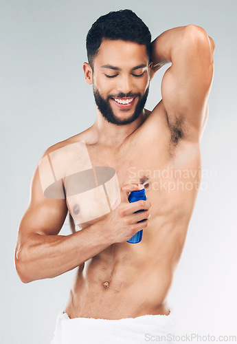 Image of Spray, armpit and man with smile for deodorant against grey studio background. Skincare, smile and strong model with antiperspirant bottle for wellness, skincare and grooming while spraying underarm
