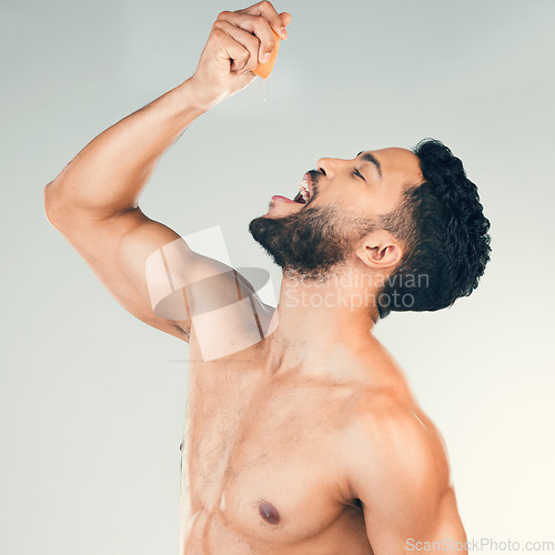 Image of Orange, juice and man eating fruit for health, nutrition and clean diet against a grey studio background. Citrus, food and healthy person with smile and happy about vitamin c for care for body