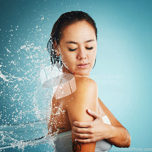 Image of Water, shower and washing with a woman in studio on a blue background for hygiene or hydration. Cleaning, cleansing and bathroom with an attractive young female in the bathroom for body care