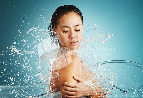 Image of Splash, water and woman in the shower to clean body against blue studio background. Skincare, relax and girl model with liquid for cleaning, wellness with hydration and hygiene for health and beauty