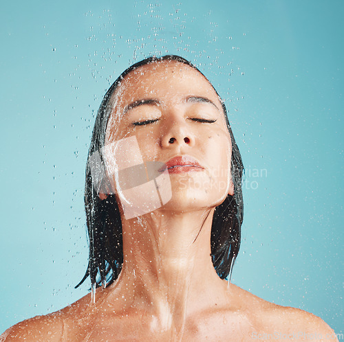 Image of Beauty, asian and woman in shower with face in water for wellness, self care and body hygiene. Health, cleaning and satisfaction of girl washing with blue studio mockup for cosmetic marketing.