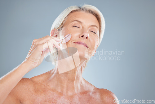 Image of Face, beauty and massage with a senior woman in studio on a gray background for skincare or wellness. Luxury, care and health with a mature female massaging her skin for natural antiaging treatment