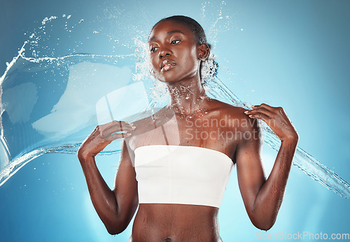 Image of Splash, skincare and black woman with water for wellness, beauty and dermatology against blue studio background. Spa, thinking and African girl model with idea for fresh, natural and body hydration