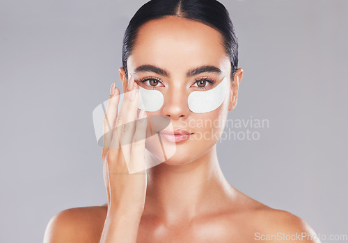 Image of Skincare, face and woman with eye patches on a gray studio background. Health, beauty or female model from Spain with facial product, cosmetics pads or collagen eye mask for hydration or anti aging