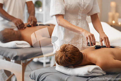 Image of Hot stone massage, black couple and relax spa in skincare wellness, healthcare or stress management in hotel salon or resort. Woman, man and massage therapist with luxury rock therapy on love retreat