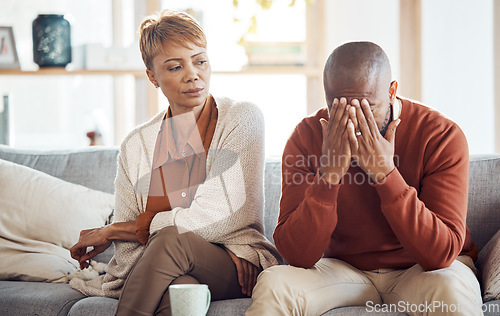 Image of Divorce, stress and mature couple arguing on the sofa in the living room of their house. Frustrated, relationship problems and upset African man and woman speaking in the lounge of their home.