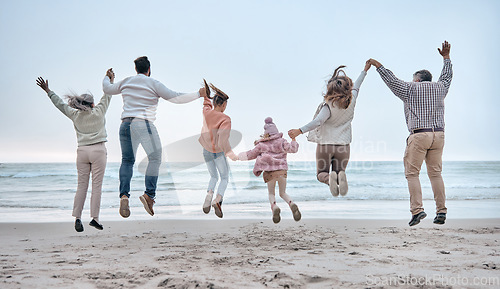 Image of Family at the beach, adventure and jump, generations love and care while holding hands and fun by the ocean. Big family travel, parents with grandparents and children together and freedom at sea.