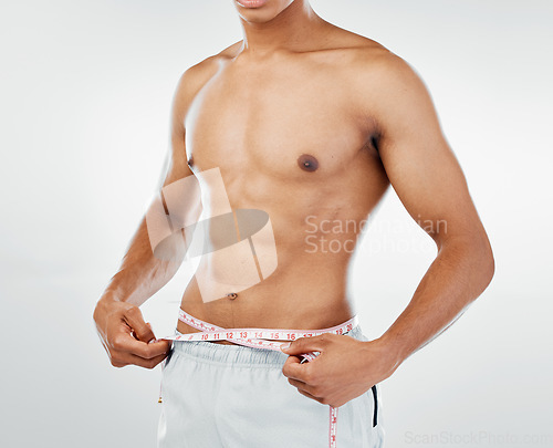 Image of Healthy bodybuilder, strong man and tape measure on stomach, weight loss progress and fitness results, diet goals and muscle gain in studio. Sports model, measuring tape and abdomen wellness check