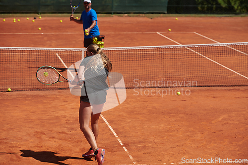 Image of A professional tennis player and her coach training on a sunny day at the tennis court. Training and preparation of a professional tennis player