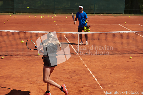 Image of A professional tennis player and her coach training on a sunny day at the tennis court. Training and preparation of a professional tennis player