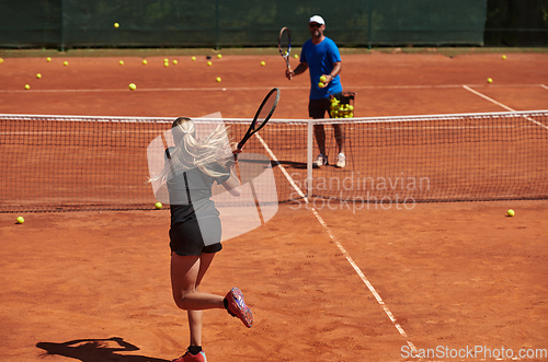 Image of A professional tennis player and her coach training on a sunny day at the tennis court. Training and preparation of a professional tennis player