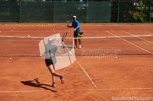 Image of A professional tennis player and her coach training on a sunny day at the tennis court. Training and preparation of a professional tennis player