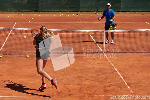 Image of A professional tennis player and her coach training on a sunny day at the tennis court. Training and preparation of a professional tennis player