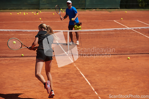 Image of A professional tennis player and her coach training on a sunny day at the tennis court. Training and preparation of a professional tennis player