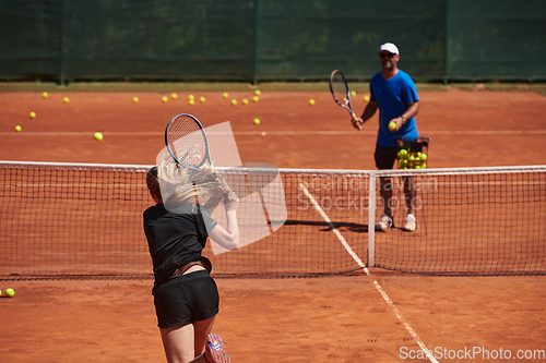 Image of A professional tennis player and her coach training on a sunny day at the tennis court. Training and preparation of a professional tennis player