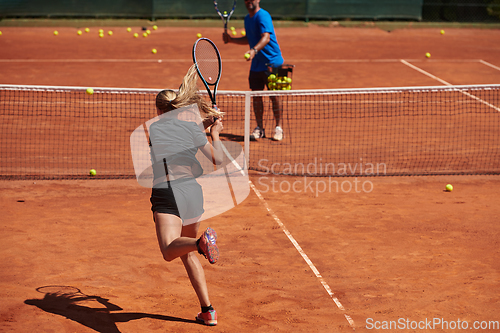 Image of A professional tennis player and her coach training on a sunny day at the tennis court. Training and preparation of a professional tennis player