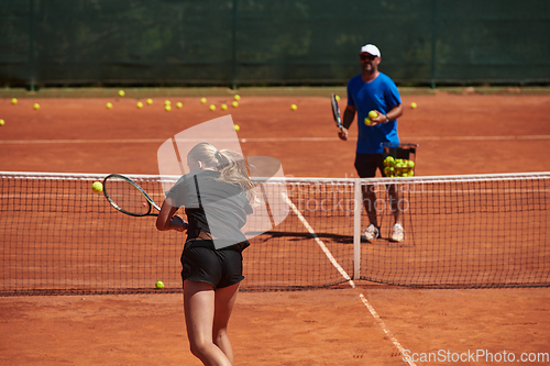 Image of A professional tennis player and her coach training on a sunny day at the tennis court. Training and preparation of a professional tennis player