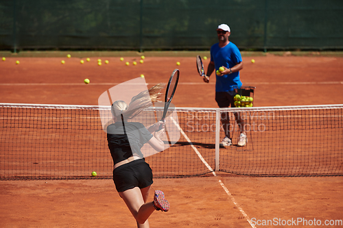 Image of A professional tennis player and her coach training on a sunny day at the tennis court. Training and preparation of a professional tennis player