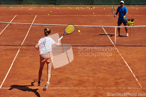 Image of A professional tennis player and her coach training on a sunny day at the tennis court. Training and preparation of a professional tennis player