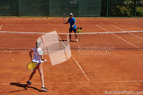 Image of A professional tennis player and her coach training on a sunny day at the tennis court. Training and preparation of a professional tennis player