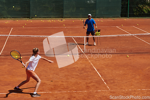 Image of A professional tennis player and her coach training on a sunny day at the tennis court. Training and preparation of a professional tennis player