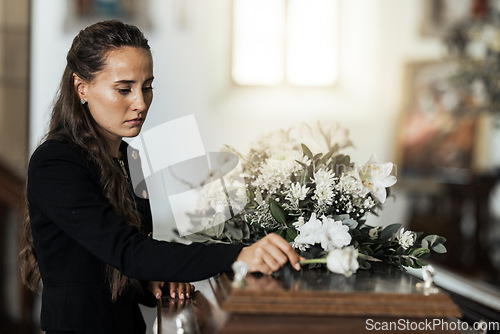Image of Funeral, sad and woman with flower on coffin after loss of a loved one, family or friend. Grief, death and young female putting a rose on casket in church with sadness, depression and mourning