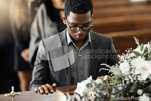 Image of Funeral coffin, death and black man sad, grieving and mourning loss of family, friends or dead loved one. Church service, floral flowers and person with casket, grief and sadness over loss of life