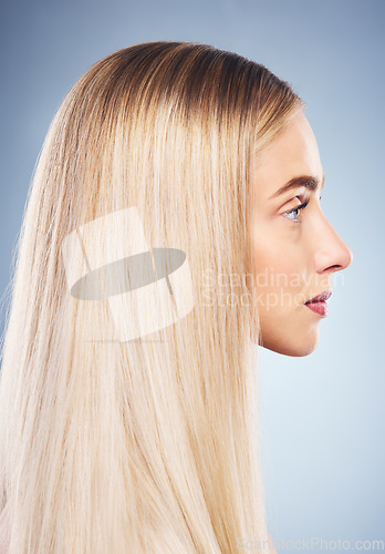 Image of Woman, side and hair with beauty, blonde and studio closeup by blue background for hair care. Model, girl and young blonde with makeup, cosmetics or shine on locks for wellness by cosmetic backdrop