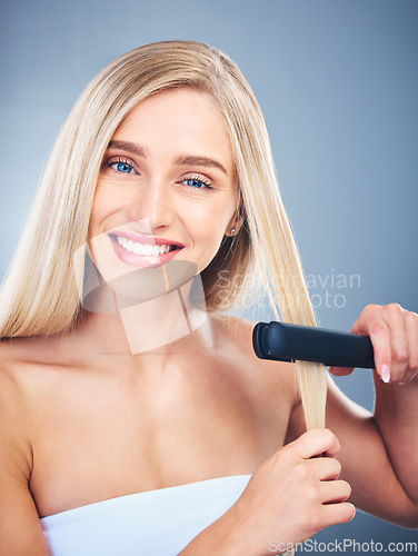 Image of Portrait of blonde happy woman, flat iron aesthetic for beauty salon and healthy hair care with natural smile. Young model with clean hair shine, studio with blue background and cosmetic heat tool