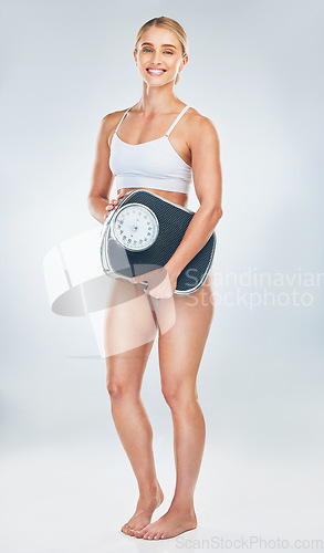 Image of Portrait, scale and woman in studio with fitness goals or calories burned targets after full body exercise or cardio workout. Happy, wellness and healthy girl fitness model on a weightloss journey