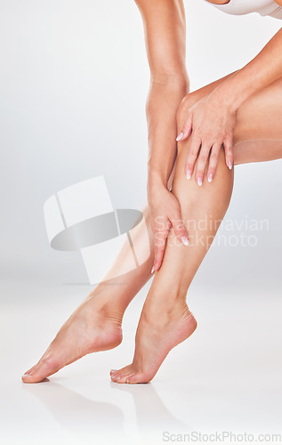 Image of Woman, hands and legs in skincare for moisturizer, smooth or soft natural care against a white studio background. Female hand touching leg to moisturize, creme or lotion for skin cosmetic treatment