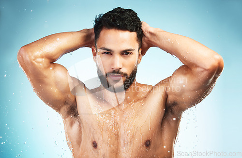 Image of Health, shower and skincarre with man in studio for health, wellness and healthy lifestyle, body wet with water on blue background. Portrait of model in studio for self care and fitness motivation