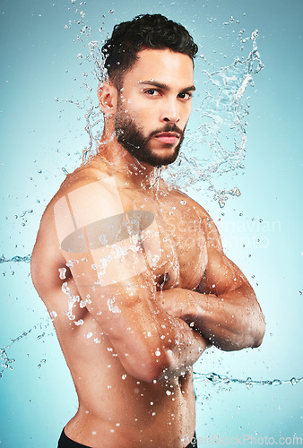 Image of Splash, water and man in hygiene and cleaning portrait, washing body and skin hydration with blue studio background. Topless model wet, skincare and grooming, fresh and clean with wellness.