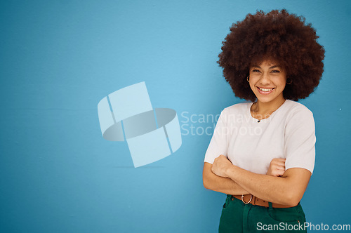 Image of Black woman, arms crossed and natural hair or afro happiness by marketing, advertising or mockup space on blue studio background. Portrait of a happy model showing smile and promotion mock up