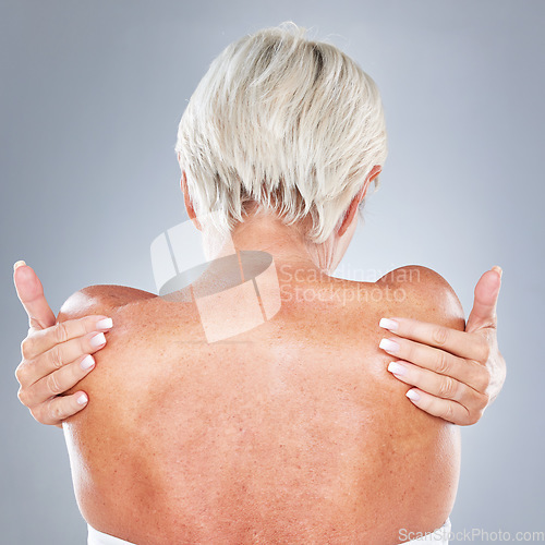 Image of Skincare, health and back of senior woman in studio on gray background for beauty, body care and spa. Healthy skin, wellness and old woman with hands on shoulders, hugging and embrace natural body