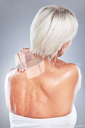 Image of Ache, pain and woman with neck injury on a grey studio background for body accident. In pain, back inflammation and physical strain of a woman anatomy from behind on a grey background.