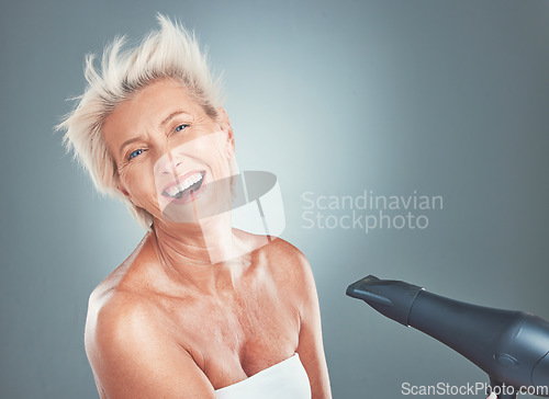 Image of Hair care, happy and senior woman with a dryer for beauty, treatment and happiness against a grey mockup studio background. Cosmetic, smile and portrait of an elderly person with a hairdryer for hair