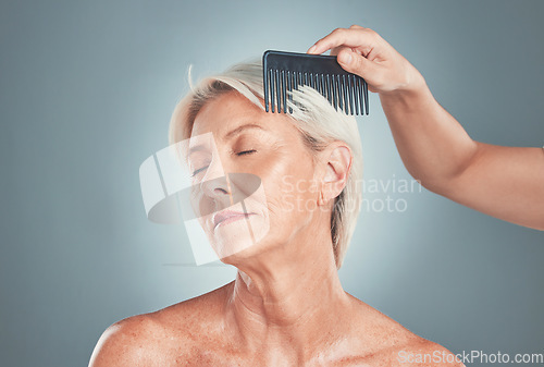 Image of Senior woman, beauty and hand comb hair for cosmetic care or wellness treatment. Elderly person, closed eyes and arm brushing healthy short locks for natural healthcare in blue backgriund studio