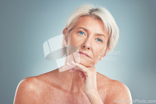 Image of Senior woman, beauty and skincare with blue eyes posing for cosmetics against a grey studio background. Portrait of a confident isolated elderly female model in pose for anti aging facial treatment